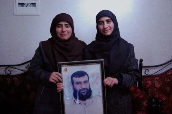Sisters Doha Ibrahim Abeyat (left) and Hind Ibrahim Abeyet hold a framed photo of their father, Ibrahim Abeyet, who was deported from the West Bank to Italy in 2002. Credit: Jillian Kestler-D’Amours/IPS.