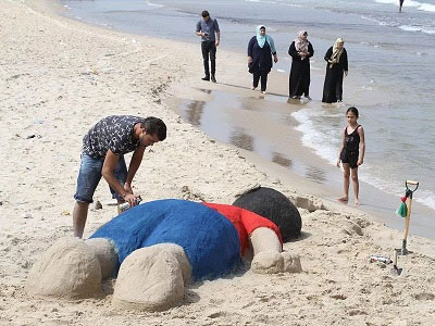 A Palestinian artist makes a sand sculpture of Aylan Kurdi in Gaza